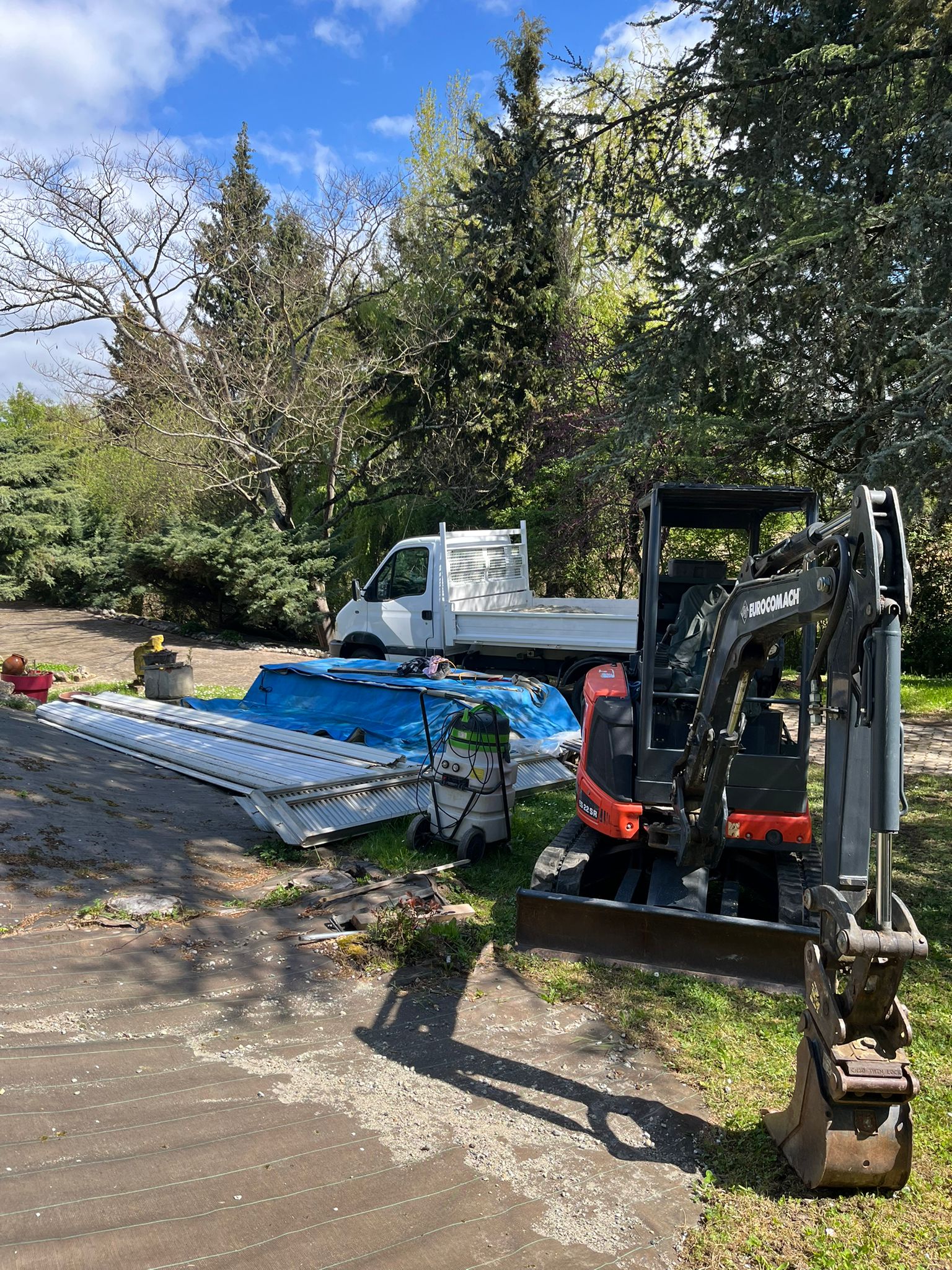 Mini-pelle Eurocomach et camion benne sur le chantier d'un chalet bois à Revel